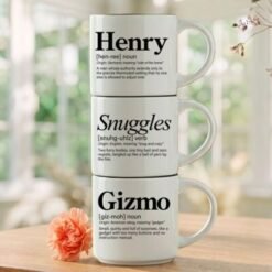 Personalized pet parent mug set reading Henry Snuggles Gizmo, three 14-ounce white stackable mugs in a black metal Storyteller Display Stand.